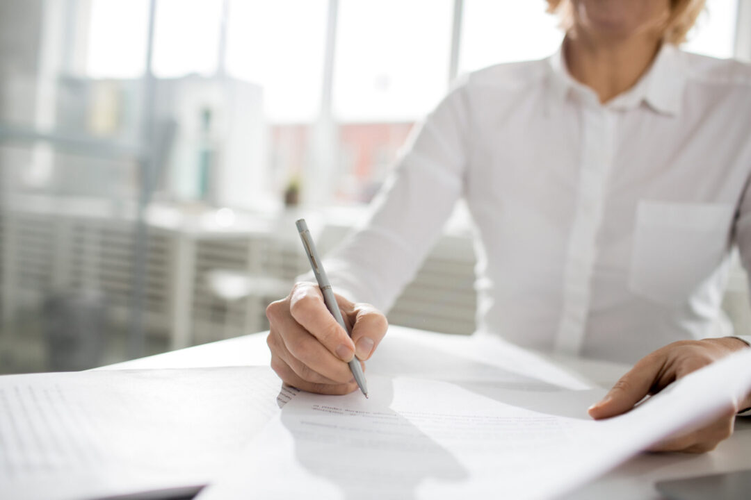 Contemporary businesswoman signing financial papers or contract in office